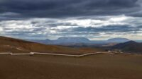 a dirt field with mountains in the background